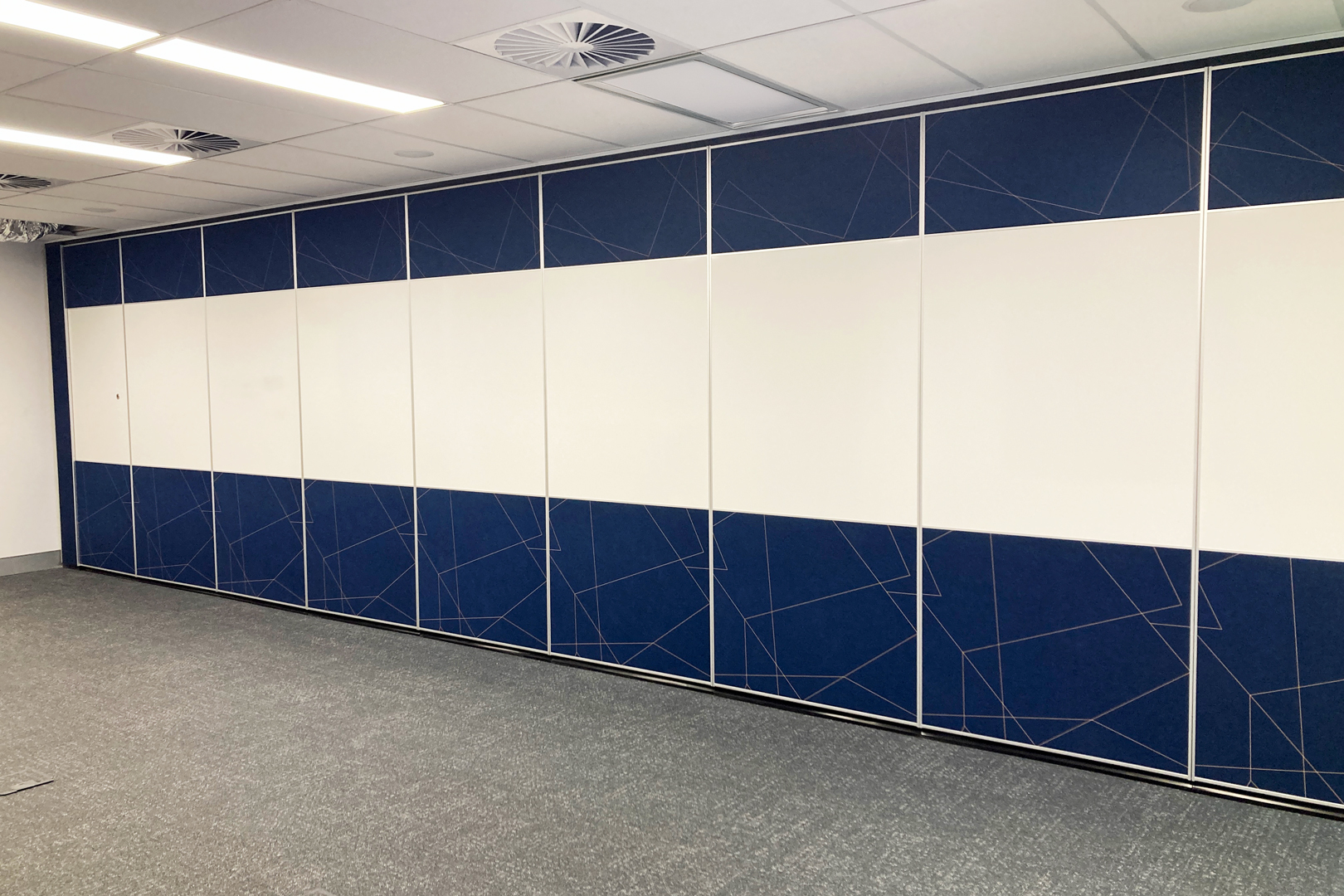 commercial installation of solid operable wall with fabric panels and whiteboard inset